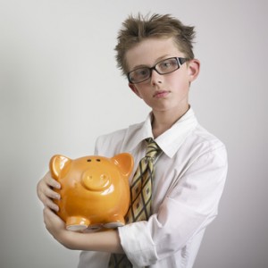 Boy wearing glasses, shirt and tie and hugging piggybank