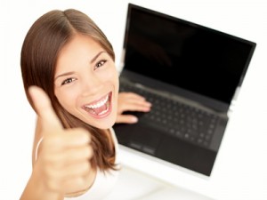 Girl with one hand on laptop, the other giving a thumbs up