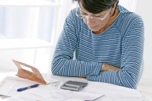 Woman with papers and calculator looking puzzled