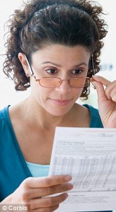 Woman holding glasses and reviewing credit card statement