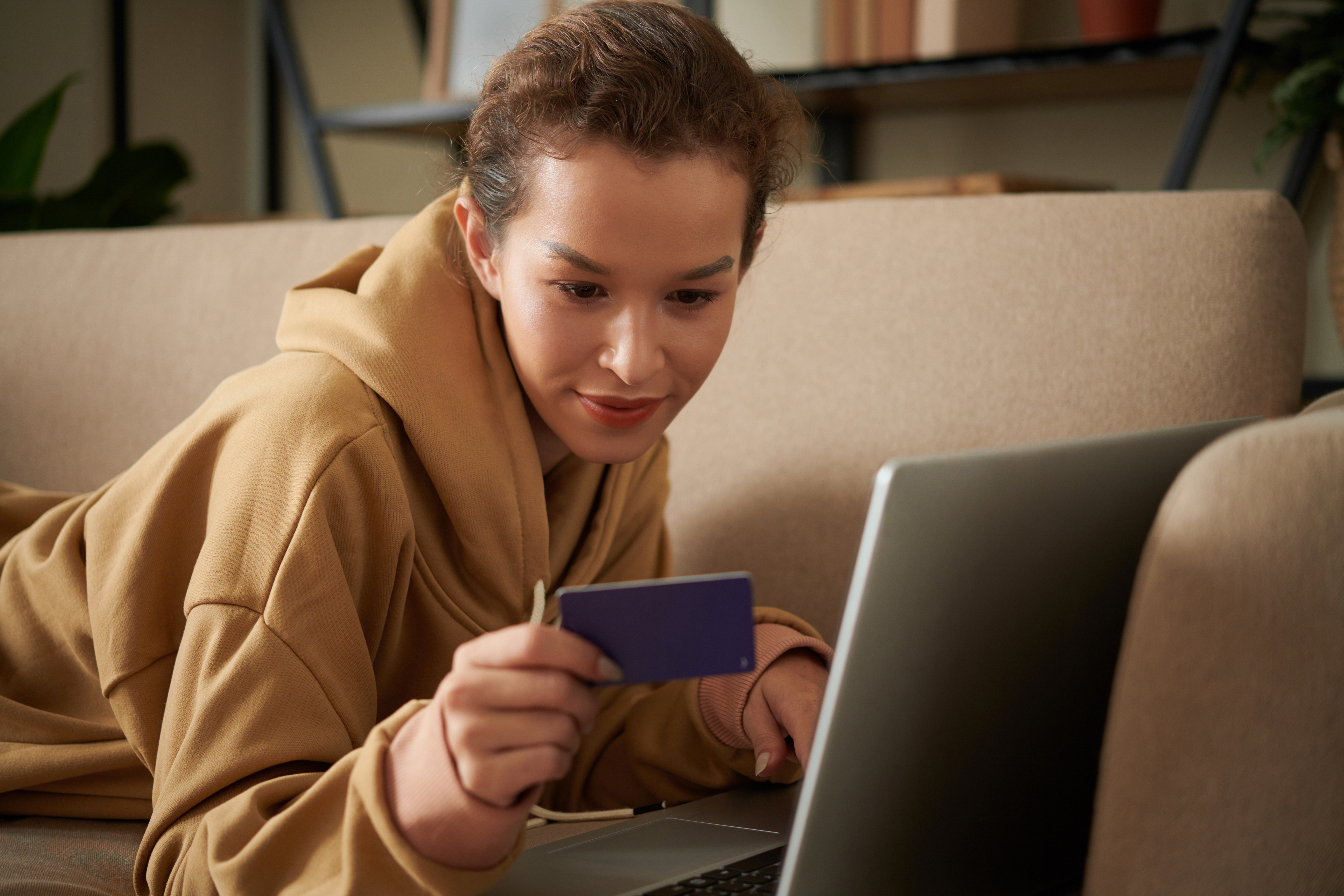 woman looking at a credit card while using her laptop