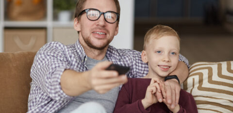 Father watching educational TV shows with son