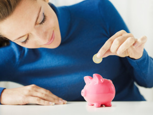 woman putting a coin in a piggy bank