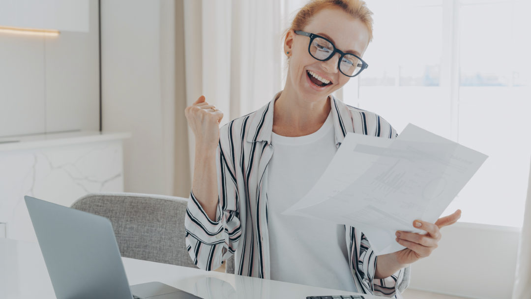 overjoyed redhead woman celebrating getting a bigger paycheck or tax refund