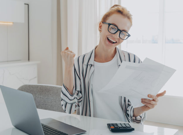 overjoyed redhead woman celebrating getting a bigger paycheck or tax refund