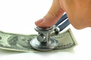hand holding a stethoscope on money