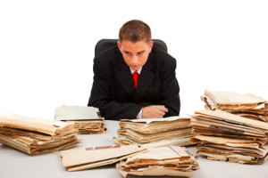 Business man looking at the huge amount of documents on table