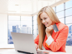 businesswoman holding a card looking at laptop