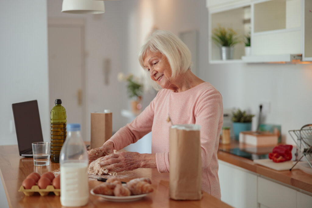 Smiling retired woman cooking while on a money diet