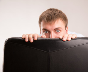 A young man hiding behind a office chair
