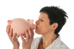 Young woman holding and kissing a piggy bank as studio portrait