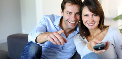 Couple watching TV woman has remote