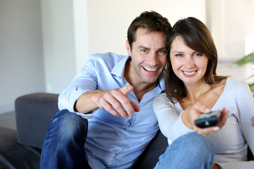 Couple watching TV woman has remote