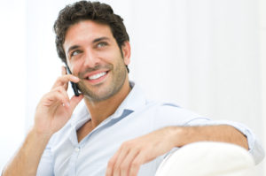 Young and healthy man smiling and talking on smart phone at home