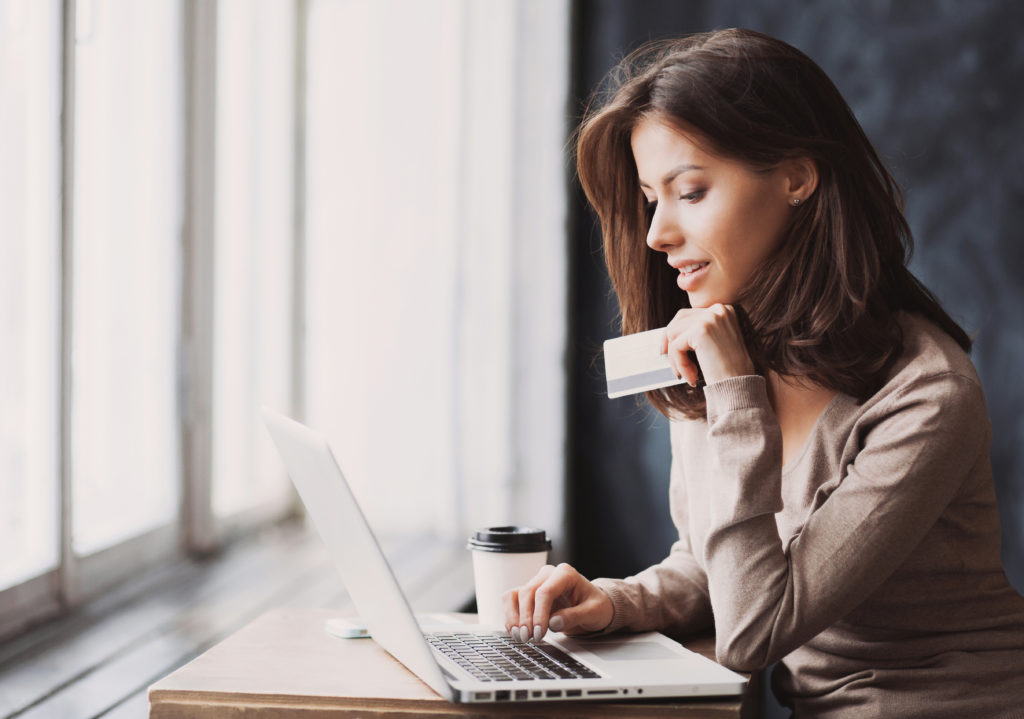 woman holding a credit card while using her laptop