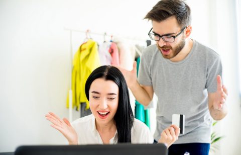 couple arguing at computer over spouse being bad with money