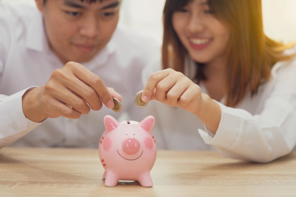 couple putting coins in a piggy bank to reach savings goals