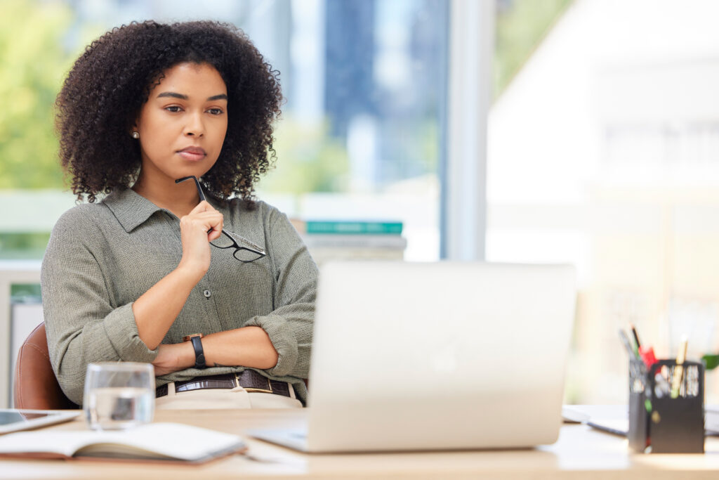 Business laptop, thinking and black woman in office trying to solve problem. Idea, focus and female employee from South Africa with computer contemplating solution, pensive or lost in thoughts alone.