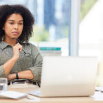 Business laptop, thinking and black woman in office trying to solve problem. Idea, focus and female employee from South Africa with computer contemplating solution, pensive or lost in thoughts alone.