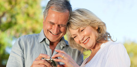 Smiling middle age couple looking at calculator e1674749357468