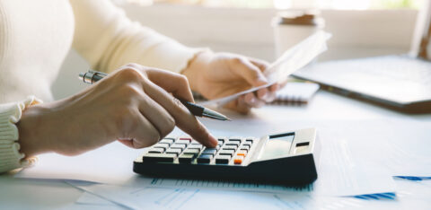 Woman managing her budget by reviewing bills, calculating expenses, and organizing financial documents at home.
