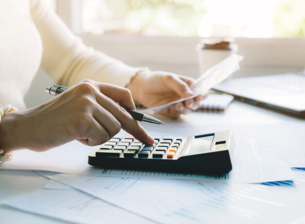Woman managing her budget by reviewing bills, calculating expenses, and organizing financial documents at home.