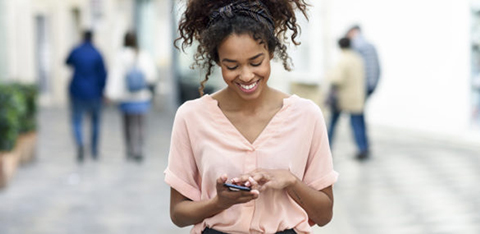 smiling young woman using cell phone in the city