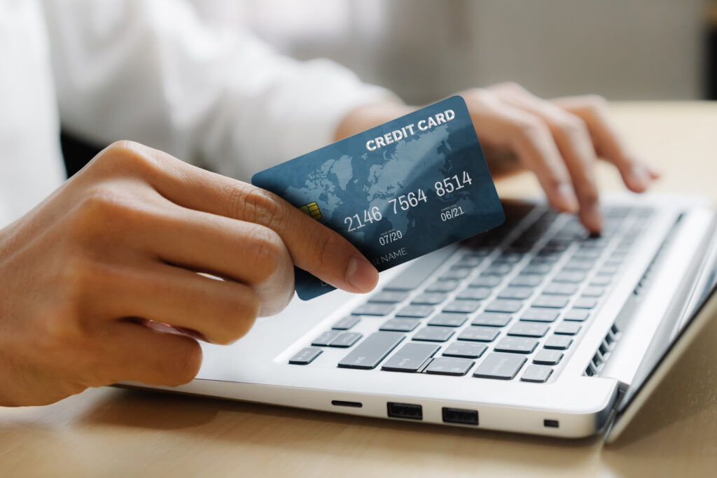 Young man use credit card for shopping payment online on laptop computer application or website. E commerce and online shopping concept.