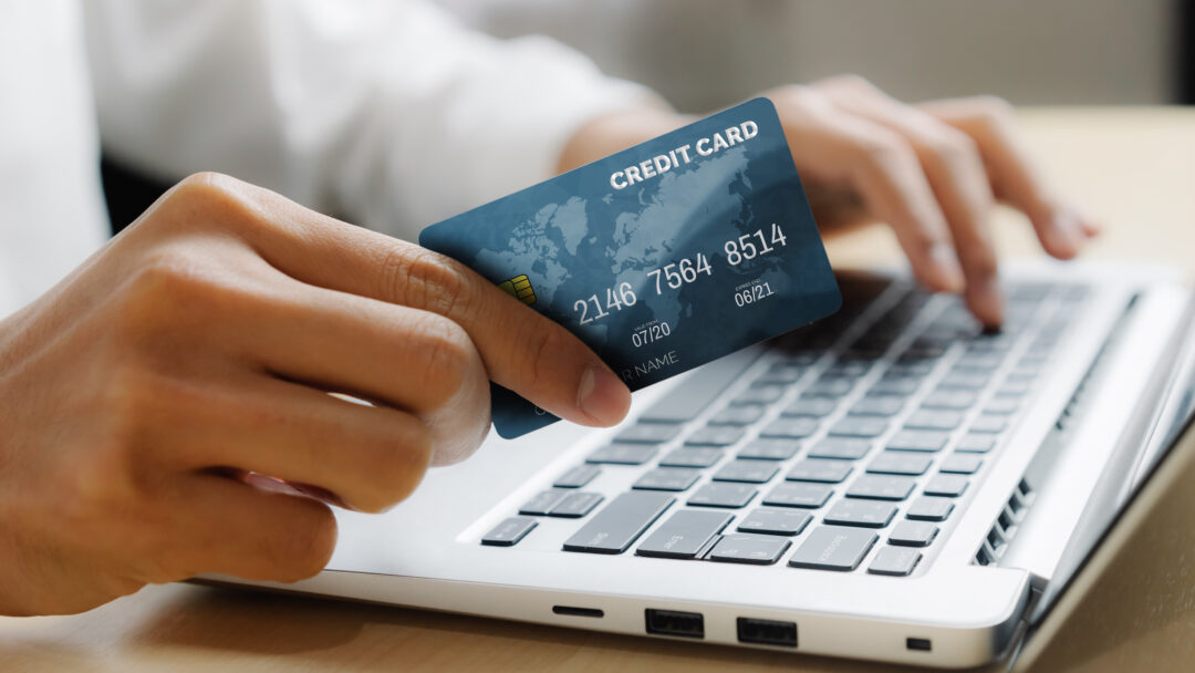 Young man use credit card for shopping payment online on laptop computer application or website. E commerce and online shopping concept.