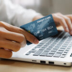 Young man use credit card for shopping payment online on laptop computer application or website. E commerce and online shopping concept.