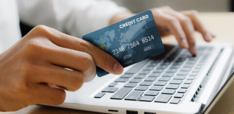 Young man use credit card for shopping payment online on laptop computer application or website. E commerce and online shopping concept.