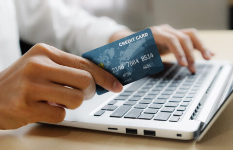 Young man use credit card for shopping payment online on laptop computer application or website. E commerce and online shopping concept.