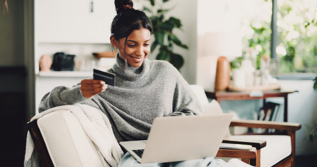 Home, laptop and woman on sofa, credit card and digital app for online banking. Ecommerce, pc and happy person on couch, electronic transaction or payment for website subscription, smile and fintech