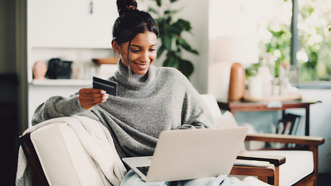 Home, laptop and woman on sofa, credit card and digital app for online banking. Ecommerce, pc and happy person on couch, electronic transaction or payment for website subscription, smile and fintech