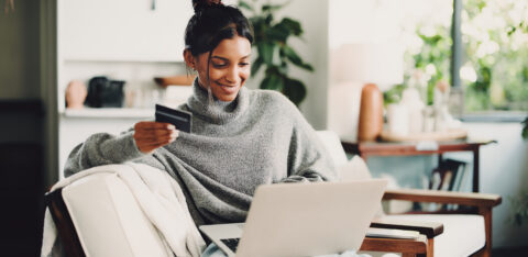 Home, laptop and woman on sofa, credit card and digital app for online banking. Ecommerce, pc and happy person on couch, electronic transaction or payment for website subscription, smile and fintech