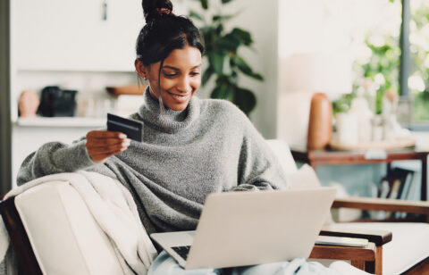 Home, laptop and woman on sofa, credit card and digital app for online banking. Ecommerce, pc and happy person on couch, electronic transaction or payment for website subscription, smile and fintech