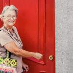female homeowner opening a red door to her home