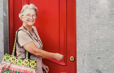 female homeowner opening a red door to her home