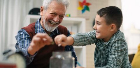 Grandpa and grandson saving money. Grandfather teaching grandchild how to save money.