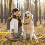 little girl playing with dog in autumn woods
