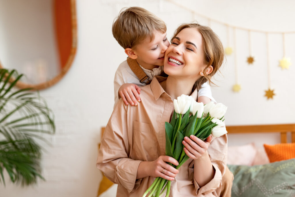 tender son kisses the happy mother and gives her a bouquet of tulips, congratulating her on mother's day