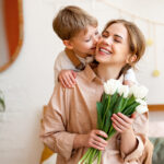 tender son kisses the happy mother and gives her a bouquet of tulips, congratulating her on mother's day