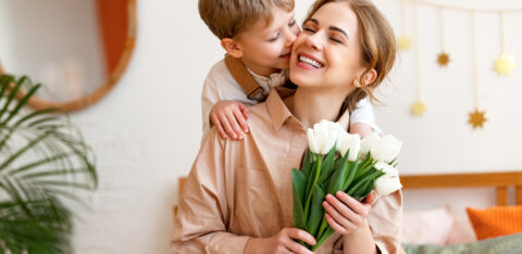 tender son kisses the happy mother and gives her a bouquet of tulips, congratulating her on mother's day