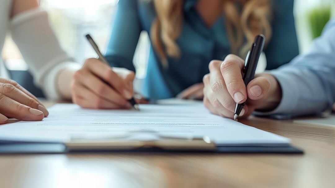 A person signing document with pen and cell phone