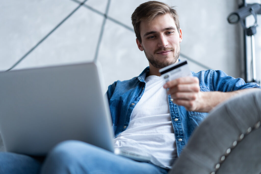 Man holding a credit card while shopping online on a laptop.