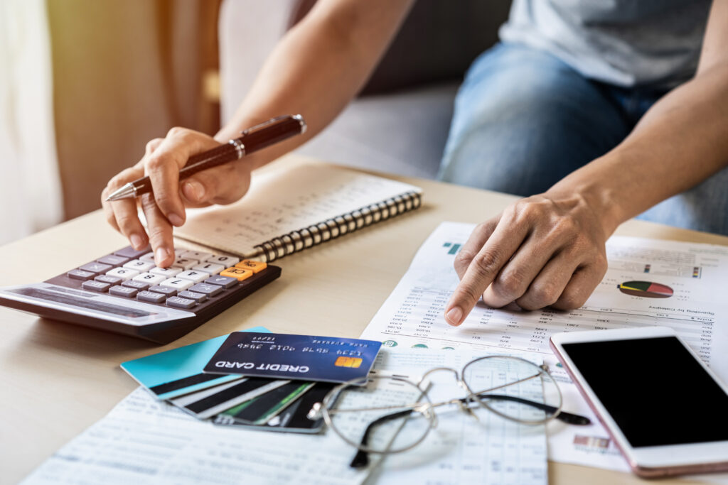 Person reviewing financial documents and using a calculator beside several credit cards.