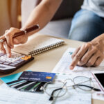 Person reviewing financial documents and using a calculator beside several credit cards.