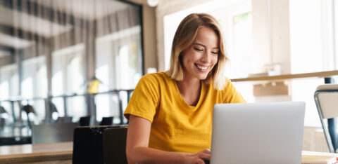 Photo of joyful nice woman using laptop and smiling while sittin