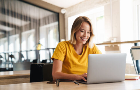 Photo of joyful nice woman using laptop and smiling while sittin