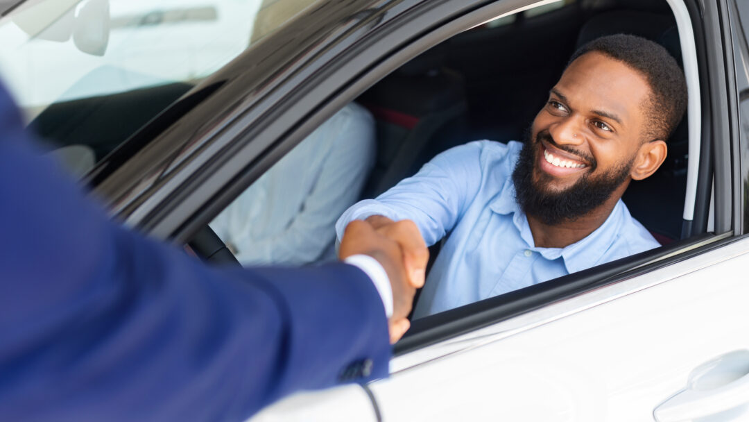 Man Sitting Inside Of New Car And Shaking Hands With Salesman